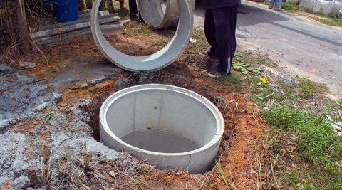 Technician uncovering a round dry well