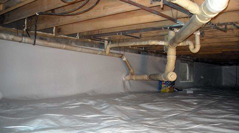 Crawl space under house foundation with pipes and insulation