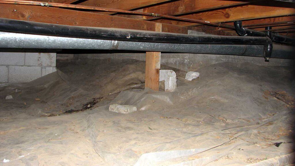 Crawl space with plastic over the dirt ground and wood beams of foundation showing