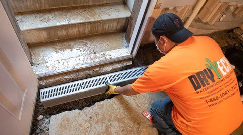 Technician installing a trench drain grate in a basement