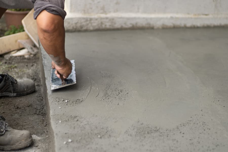 worker smoothing cement on work site