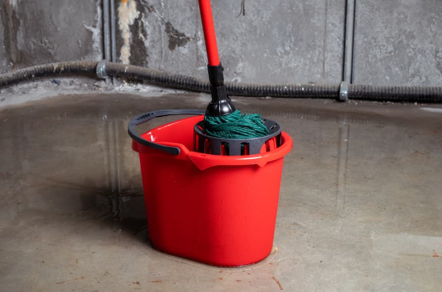 Mop and bucket in flooded basement caused by sump pump malfunction