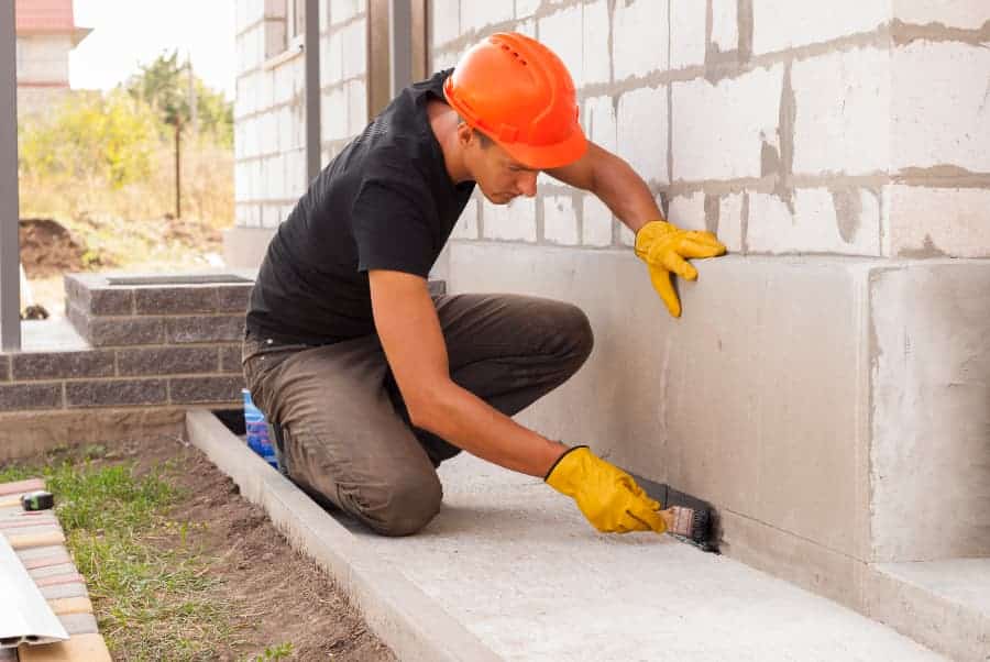 Worker applies mastic on the foundation